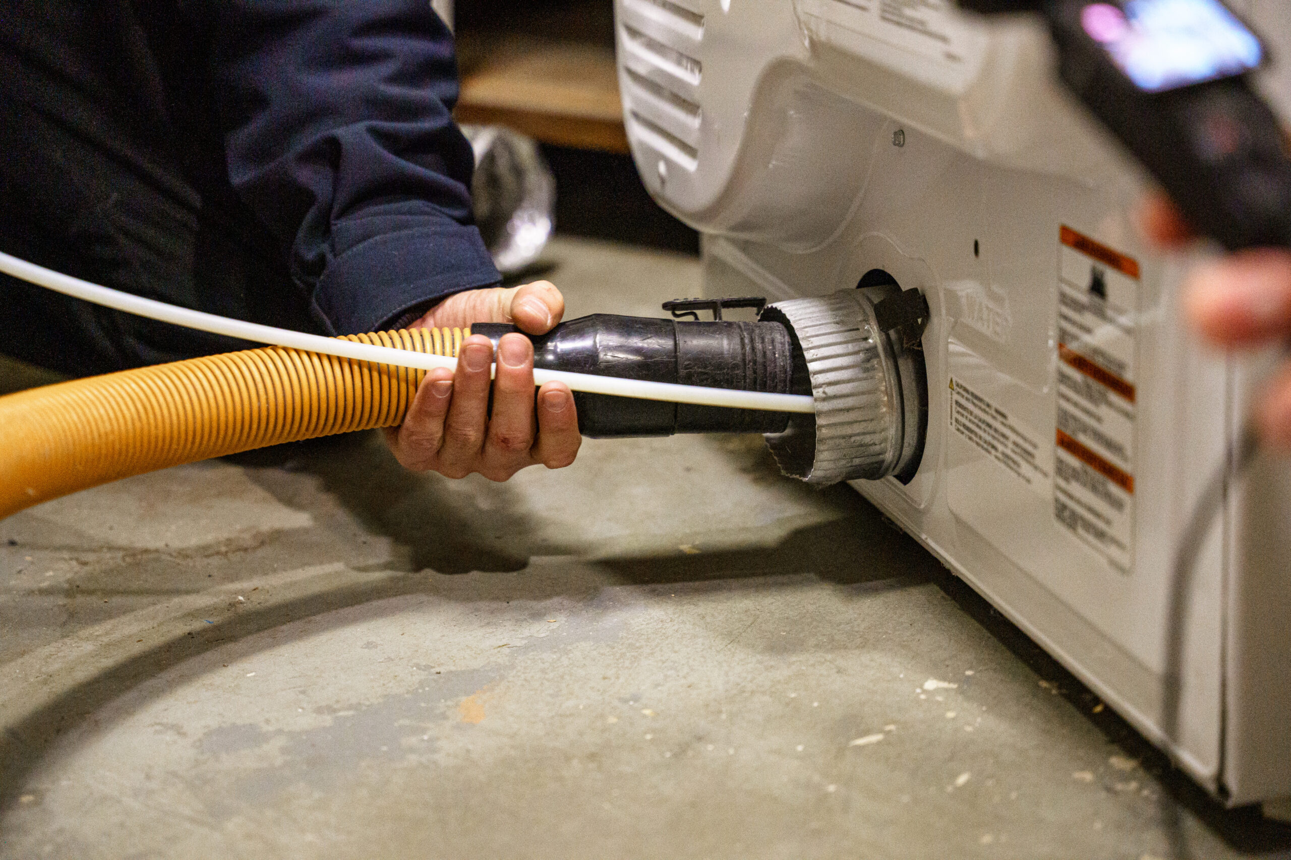 C-DET certified dryer vent technician performing a dryer vent cleaning